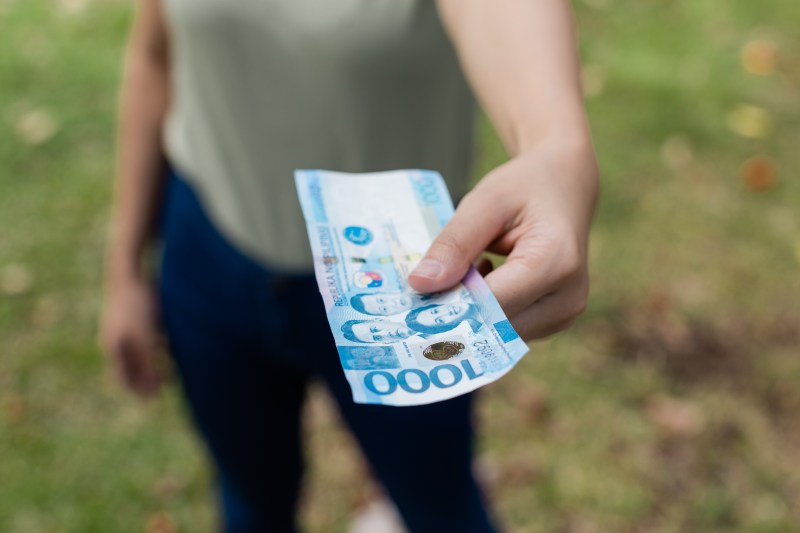 image of person holding Philippine pesos in hand